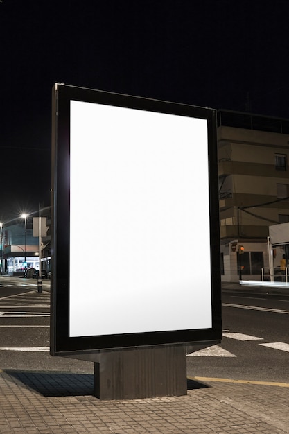 Cartel en blanco vertical en la calle por la noche