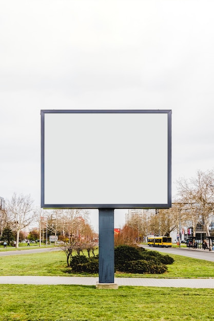 Foto gratuita cartel de cartelera de calle vertical en blanco en la hierba verde en el camino de la ciudad