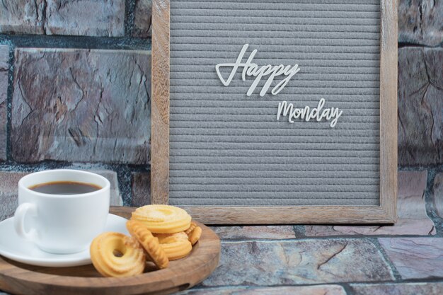 Cartel de feliz lunes con una taza de bebida y galletas alrededor