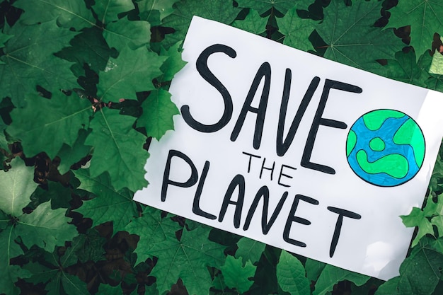 Cartel con la inscripción salvar el planeta en el bosque entre las plantas
