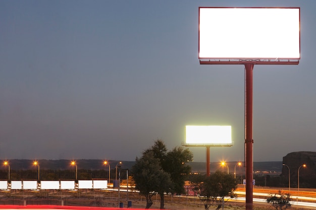 Cartelera en blanco blanco sobre la carretera iluminada durante la noche