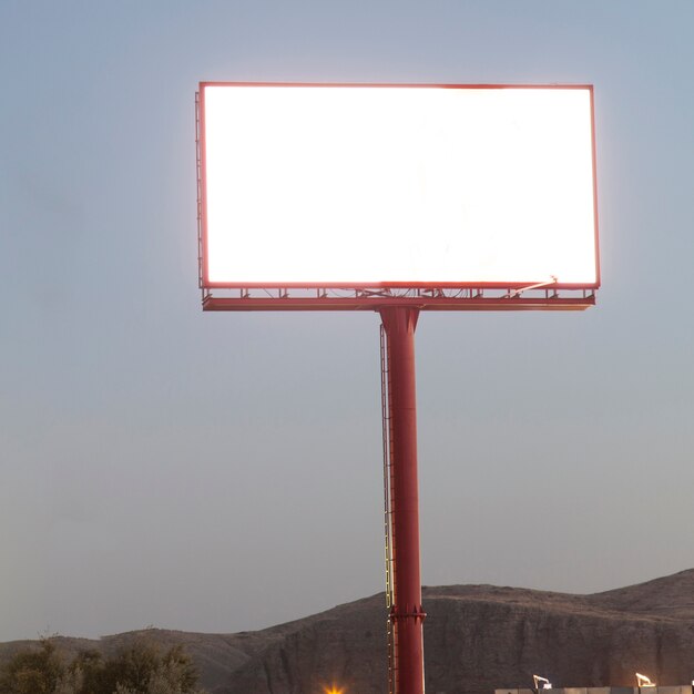 Cartelera en blanco iluminada para el anuncio contra el cielo azul