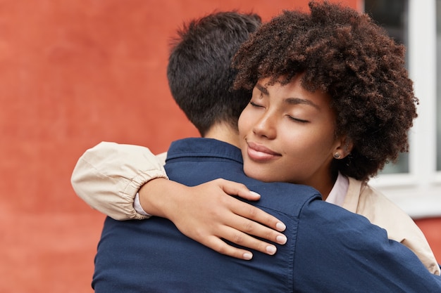 Foto gratuita carying mujer abraza a su novio, ha complacido la expresión facial