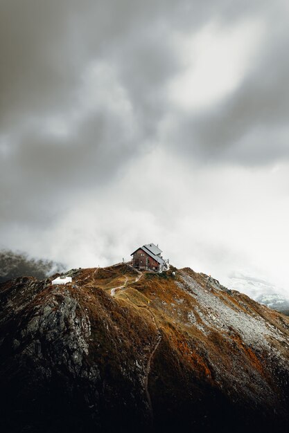 Casa blanca y marrón en la cima de la montaña marrón bajo nubes blancas