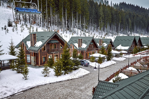 Casa de madera de vacaciones de vacaciones de invierno en las montañas cubiertas de nieve y cielo azul. Esquís en frente de la casa.