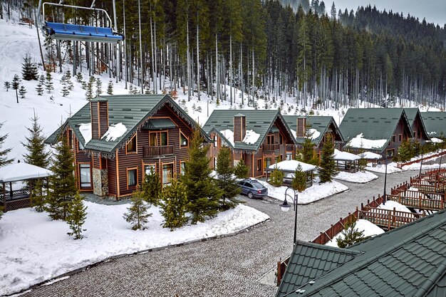 Casa de madera de vacaciones de vacaciones de invierno en las montañas cubiertas de nieve y cielo azul. Esquís en frente de la casa.