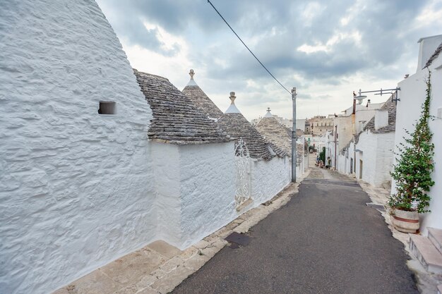 Casco antiguo vacío de Alberobello con casas Trulli entre plantas verdes y flores, principal distrito turístico, región de Apulia, sur de Italia. Edificios típicos construidos con muros de piedra seca y cubierta cónica