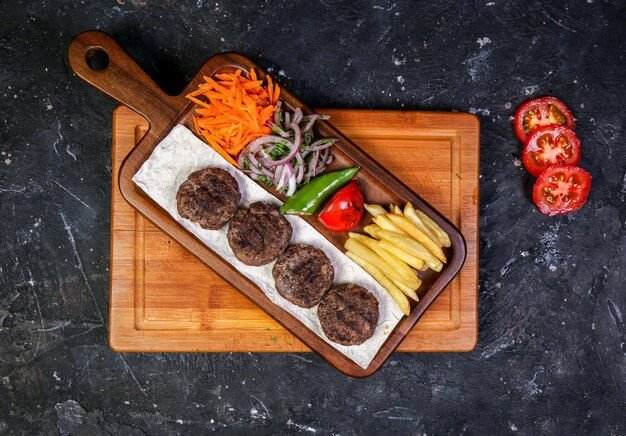 Casitas de carne con ensalada de verduras y papas fritas.