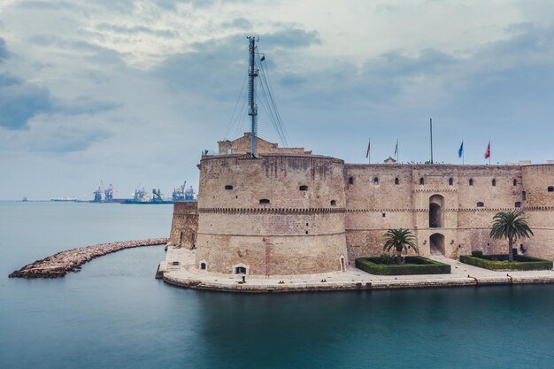 Castillo aragonés de Taranto y puente giratorio sobre el canal entre el Mar Grande y el Pequeño. Cielo azul de la tarde de una gran ciudad en Italia con un puerto industrial.