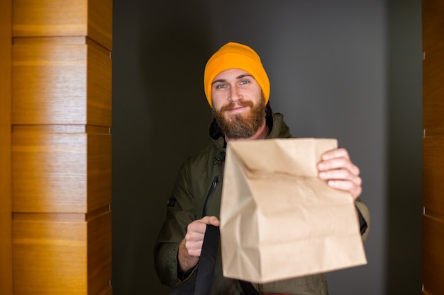 Caucásico entrega hombre manipulando la caja con comida adentro, dárselo al cliente en la puerta. Servicio de entrega durante covid19.