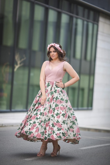 Caucásico parado frente a un edificio moderno con un vestido rosa y una diadema