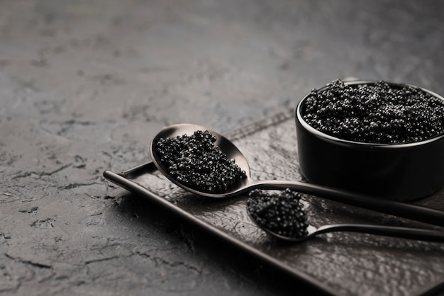 Caviar negro en un tazón con cucharas y cucharón
