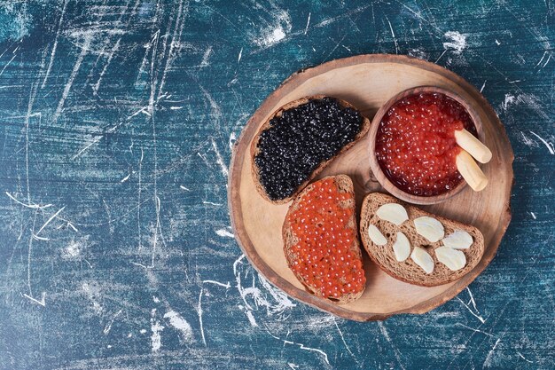 Caviar rojo y negro sobre tabla de madera.