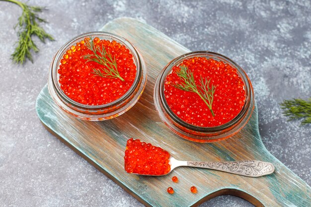 Caviar rojo en recipiente de vidrio y en una cuchara, vista superior