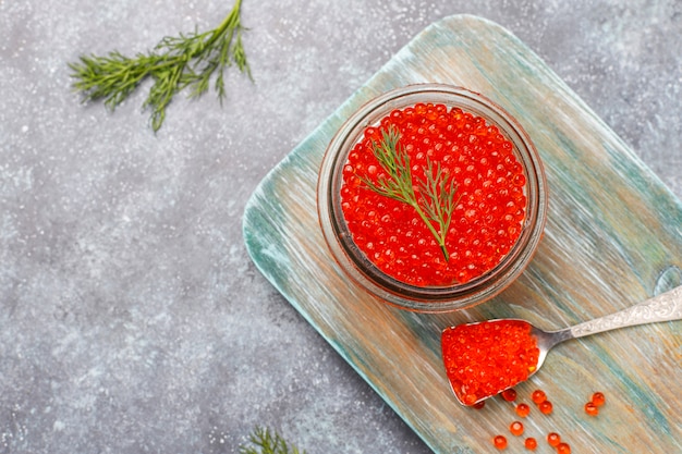 Caviar rojo en recipiente de vidrio y en una cuchara, vista superior