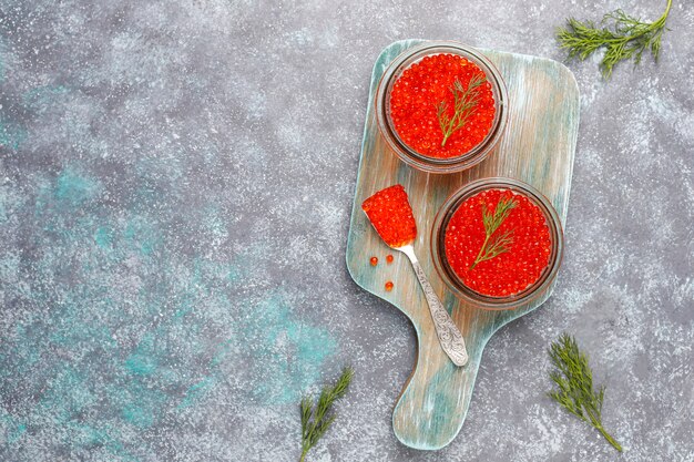 Caviar rojo en recipiente de vidrio y en una cuchara