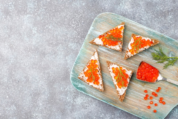 Caviar rojo en recipiente de vidrio y en una cuchara