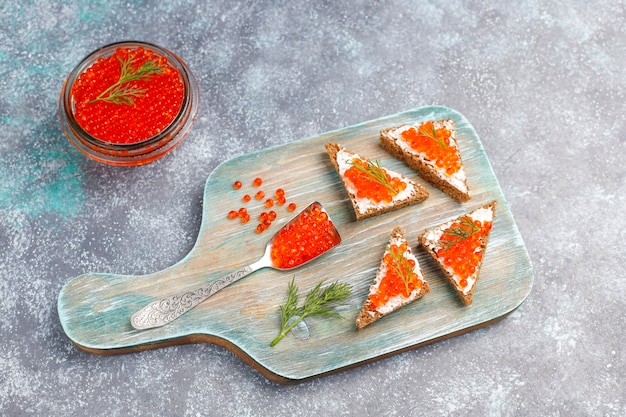 Caviar rojo en recipiente de vidrio y en una cuchara