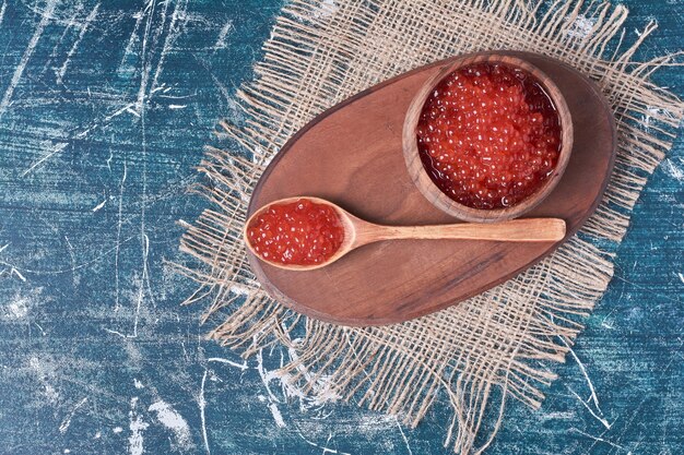 Caviar rojo sobre tabla de madera, vista superior.