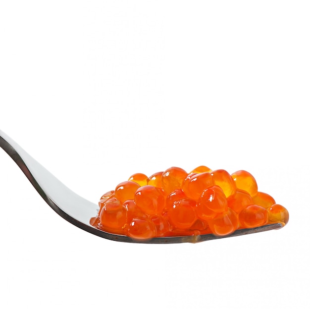Caviar rojo en un tenedor aislado en mesa blanca