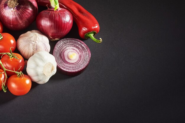 Cebolla y ajo y pimientos picantes y tomates aislados en un negro.