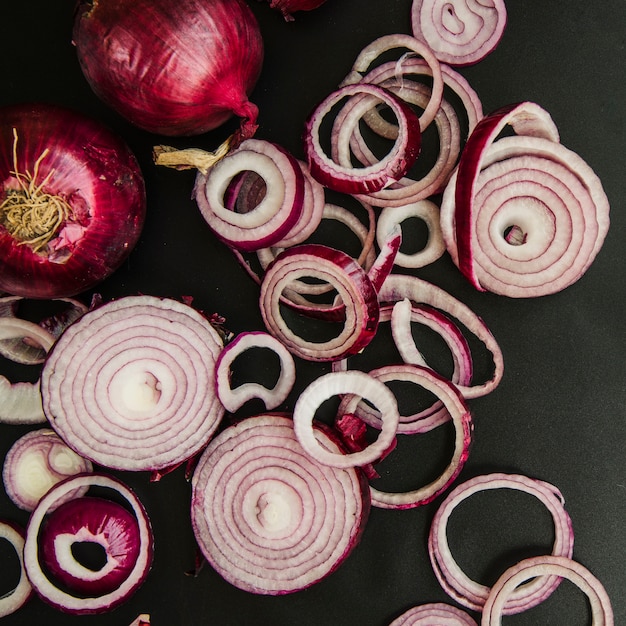 Cebolla entera y rodajas sobre la parte superior de la cocina negra.