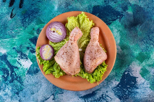 Cebolla hojas de lechuga y muslo de pollo en una placa de arcilla