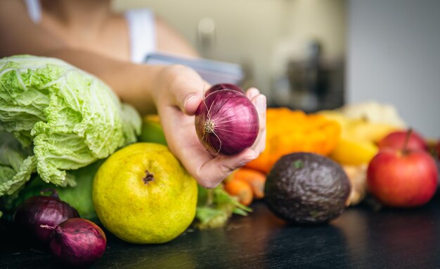 Cebolla de primer plano en manos femeninas sobre un fondo borroso de la cocina