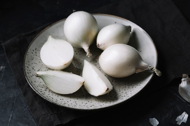 Cebollas blancas en un plato con fondo negro