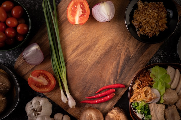 Foto gratuita cebolletas, pimientos, ajo y setas shiitake en una placa de madera