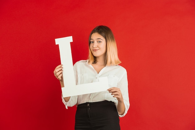 Celebración del día de San Valentín, feliz, linda chica caucásica con carta en estudio rojo