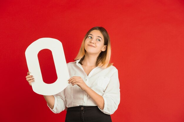 Celebración del día de San Valentín, feliz niña caucásica sosteniendo una carta sobre fondo rojo.