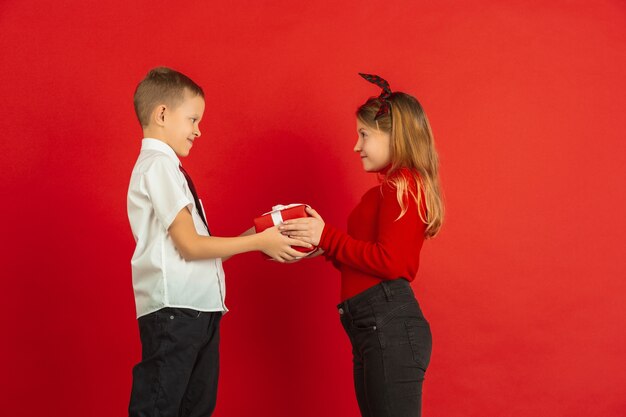 Celebración del día de San Valentín, niños caucásicos felices aislados sobre fondo rojo