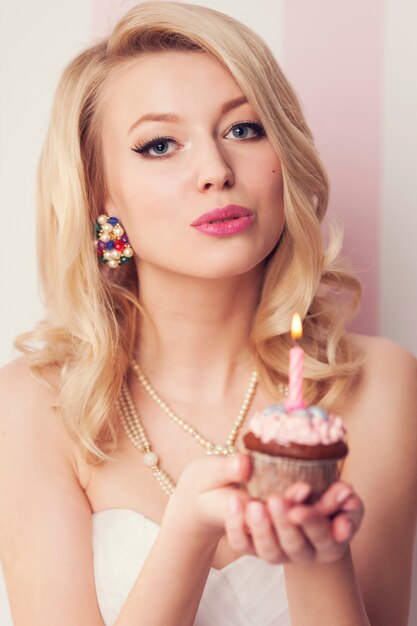 Celebración de hermosa mujer rubia con muffin y vela