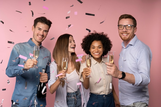 Celebración de hombres y mujeres con copas de champán y confeti.