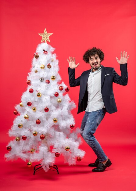 Celebración de Navidad con feliz divertido joven bailando y de pie cerca del árbol de Navidad