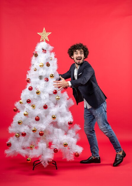 Celebración de Navidad con joven gracioso emocionado feliz abrazando el árbol de Navidad