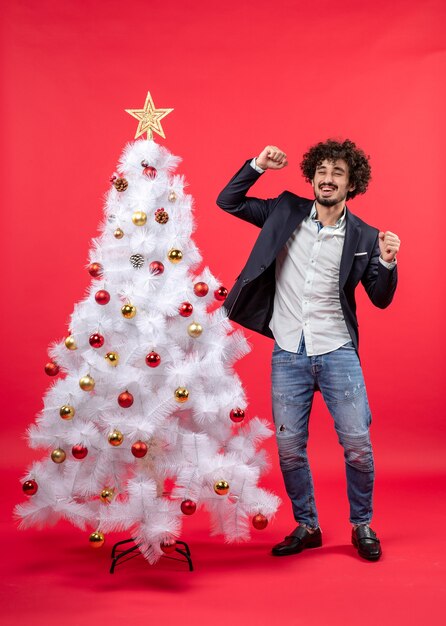 Celebración de Navidad con joven gracioso emocionado feliz bailando cerca del árbol de Navidad