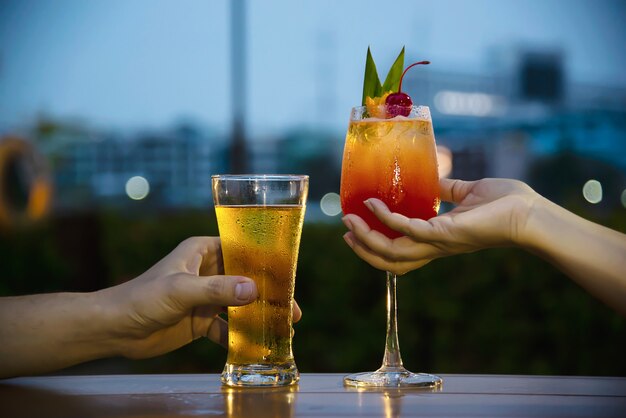 Celebración de pareja en restaurante con refrescos cerveza y mai tai o mai thai