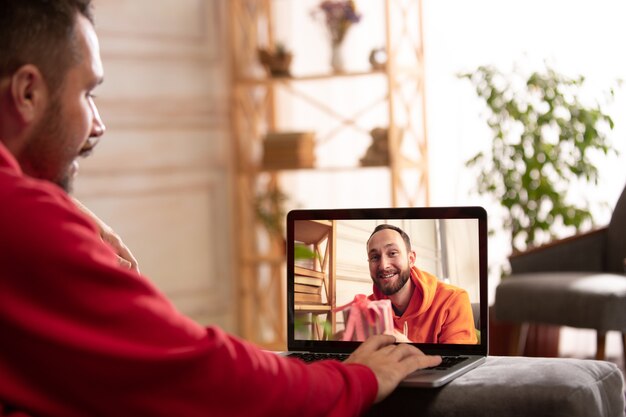 Celebración y vacaciones durante el concepto de cuarentena. Amigos o familiares desempacando regalos mientras hablan mediante videollamada. Luce feliz, alegre, sincera. Concepto de año nuevo, tecnologías, emociones.