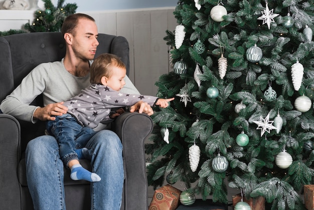 Celebraciones de navidad con hombre y niño al lado de árbol de navidad