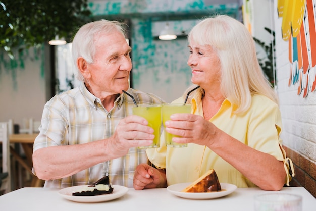 Celebrando alegre pareja de ancianos con bebidas