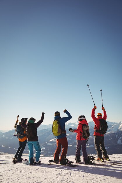 Celebrando a los esquiadores de pie en la montaña cubierta de nieve