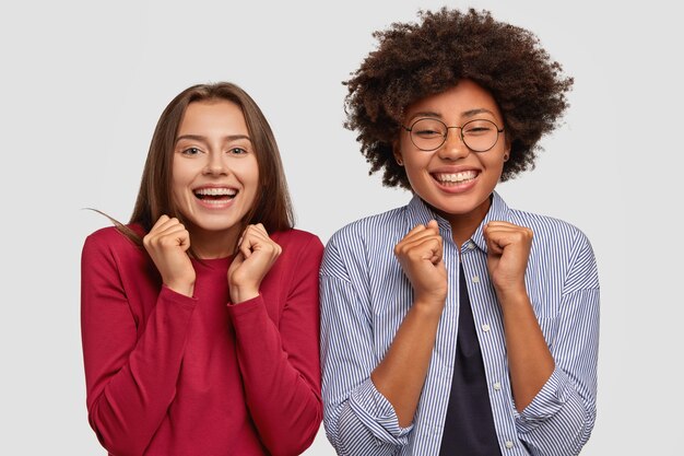 Celebrando el éxito de las mujeres multiétnicas que aprietan los puños en señal de triunfo