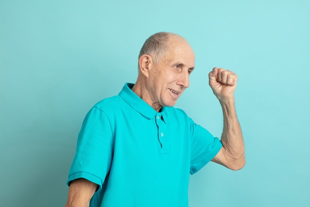 Foto gratuita celebrando la victoria, confiado. retrato de hombre mayor caucásico en estudio azul.