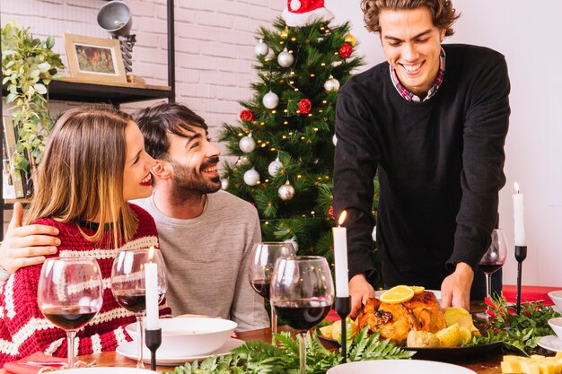 Cena de navidad con pavo y amigos sonrientes