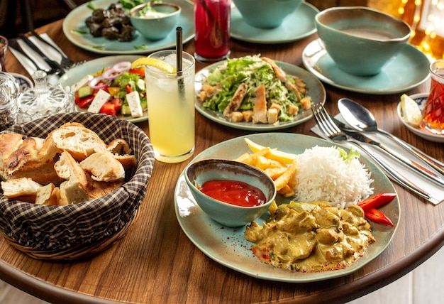 Cena con pollo servido con arroz y papas fritas César y ensaladas de verduras y limonada