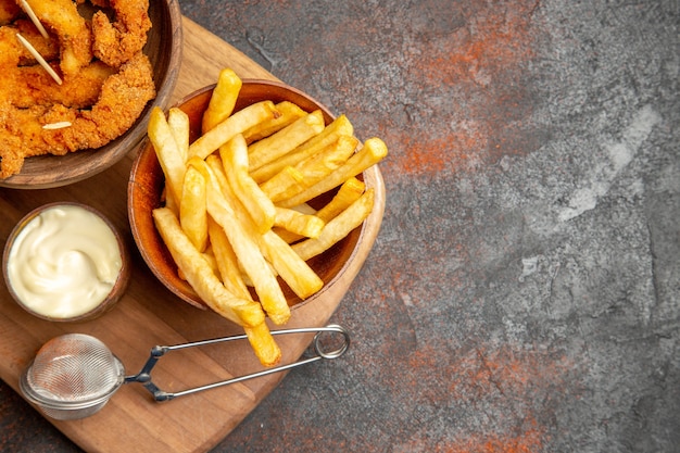 Cena sabrosa con pollo frito crujiente y patatas con mayonesa y ketchup.