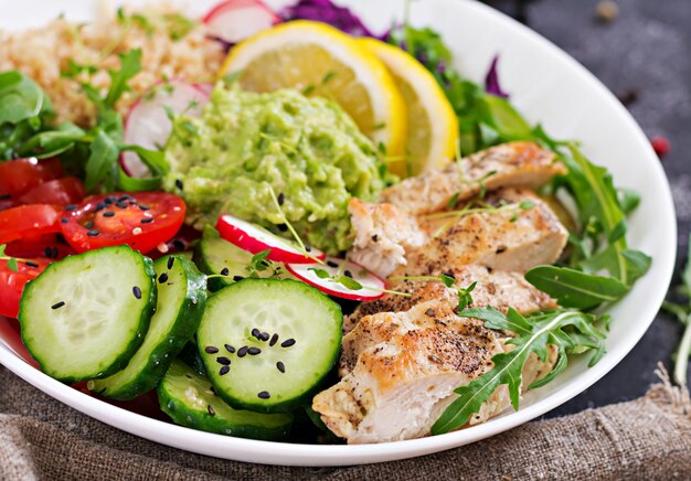 Cena Saludable. Buda tazón almuerzo con pollo a la parrilla y quinua, tomate, guacamole, repollo rojo, pepino y rúcula.