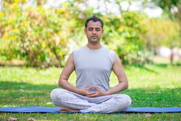 Centrado joven indio meditando en posición de loto.